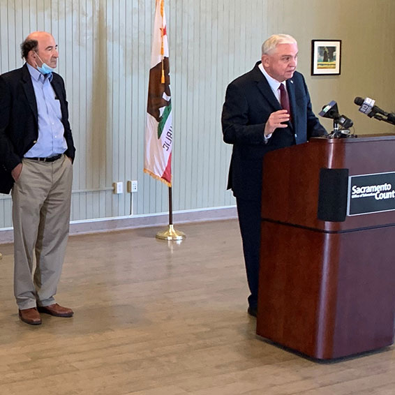 Dave Gordon speaking at podium with Peter Beilenson standing nearby