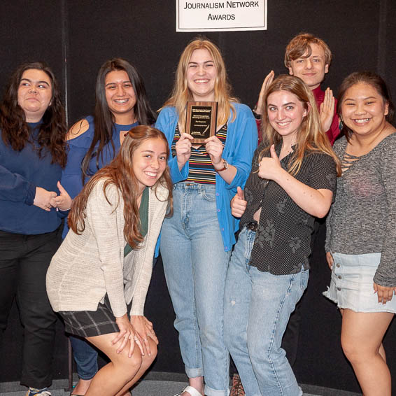 Group of smiling students holding plaque