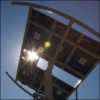 Sun shining between gaps in solar panels overhead