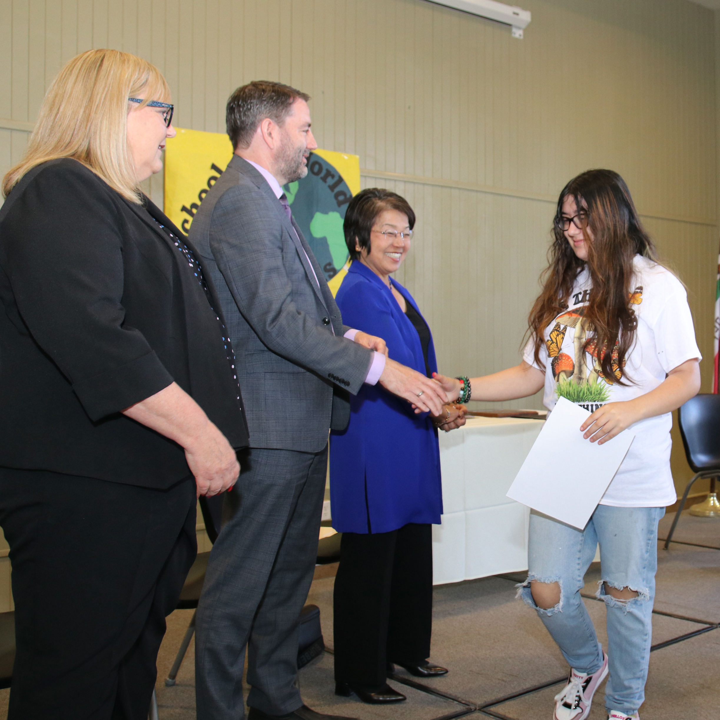 Lauren Roth, Michael Kast, and Nancy Herota shaking hands with student