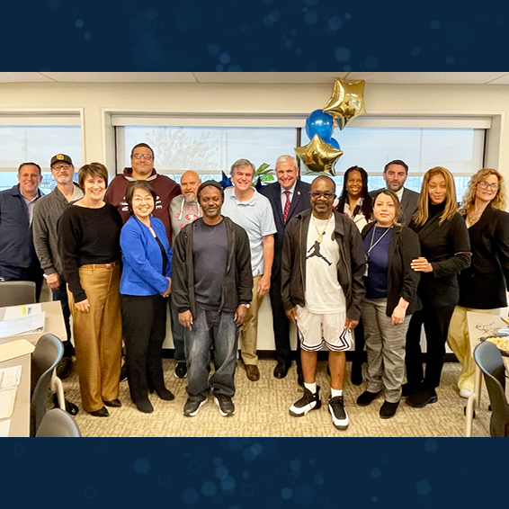 Group of clients, staff, and administrators posing with Bill Garvey