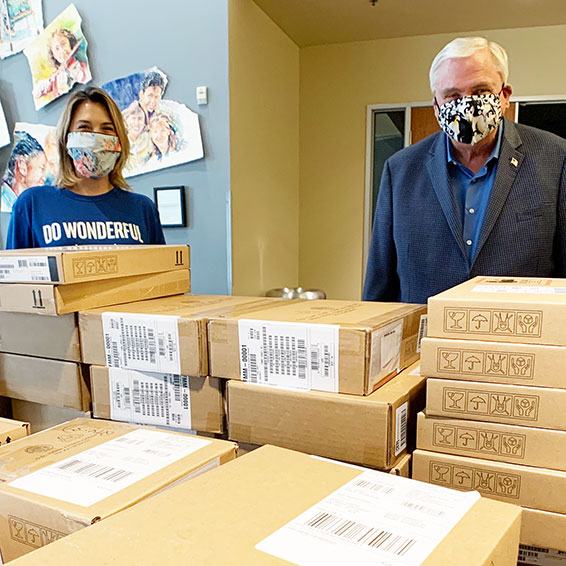 Anna Ballard and Dave Gordon standing behind a stack of cardboard laptop boxes.