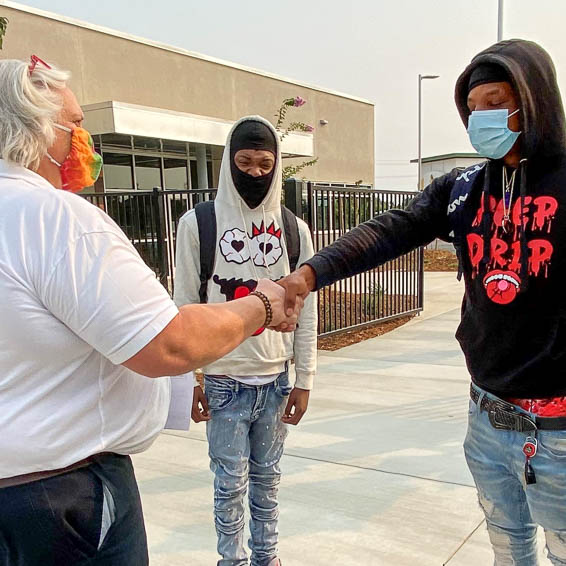 Students shaking hands with school staff