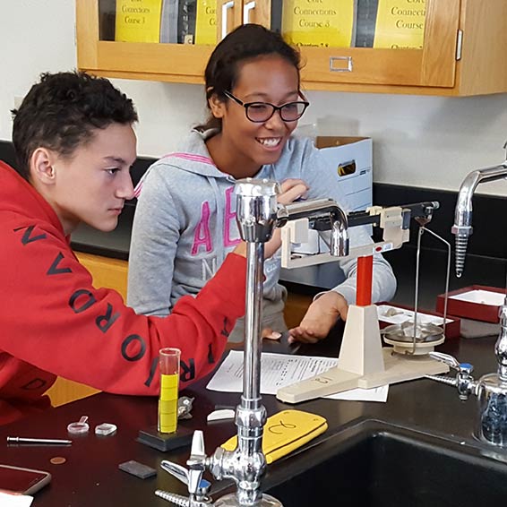 Students in science classroom using scale