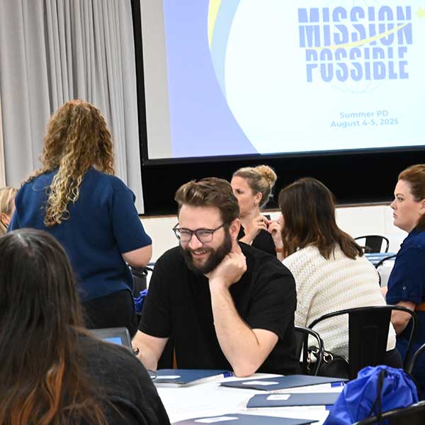Staff sitting in front of 'Mission Possible' logo projected on screen