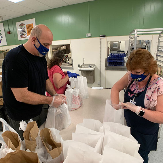 Sly Park kitchen staff, wearing masks, prepare bagged student meals