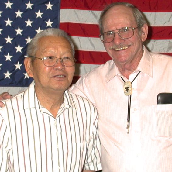 Two Operation Recognition diploma recipients pose in front of an American flag