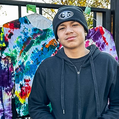 Student posing in front of tie dye t-shirts
