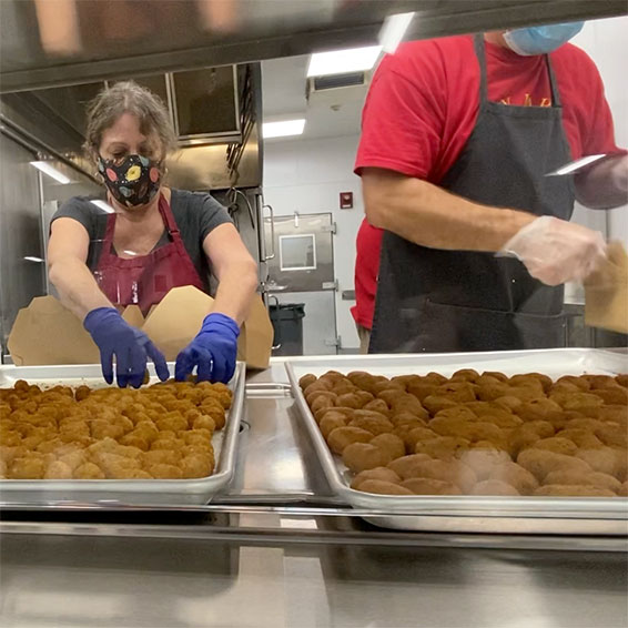 Staff packaging trays of food in industrial kitchen