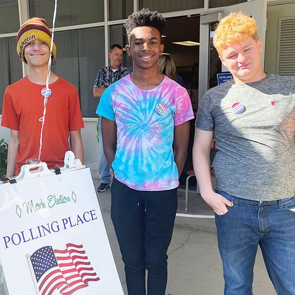 Students posing with Mock Election Polling Place sign