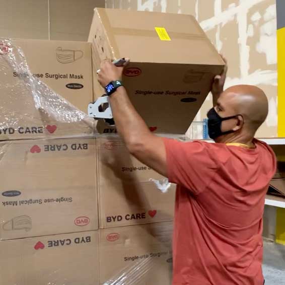 Staff member lifting box of surgical masks off a pallet