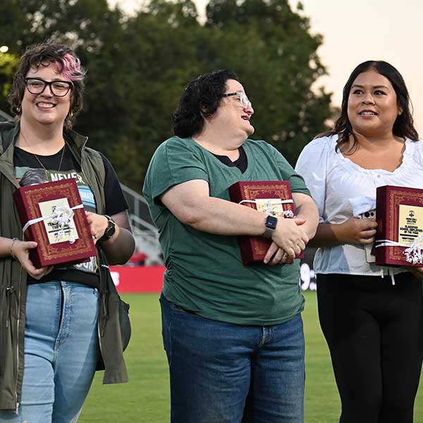 Staff holding red books with plaques