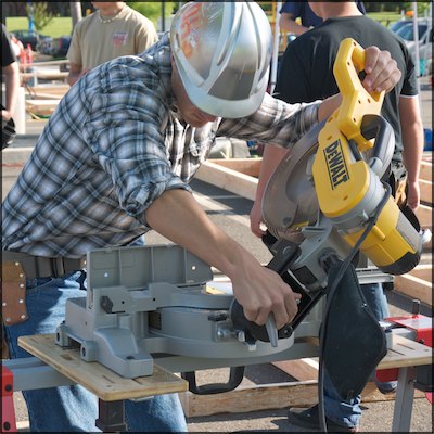 Student in hard hat adjusting miter saw