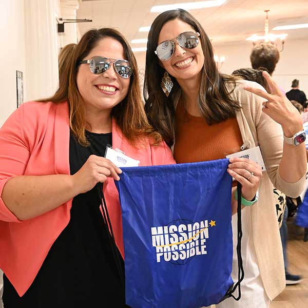 Staff posing with custom 'Mission Possible' dawstring bag