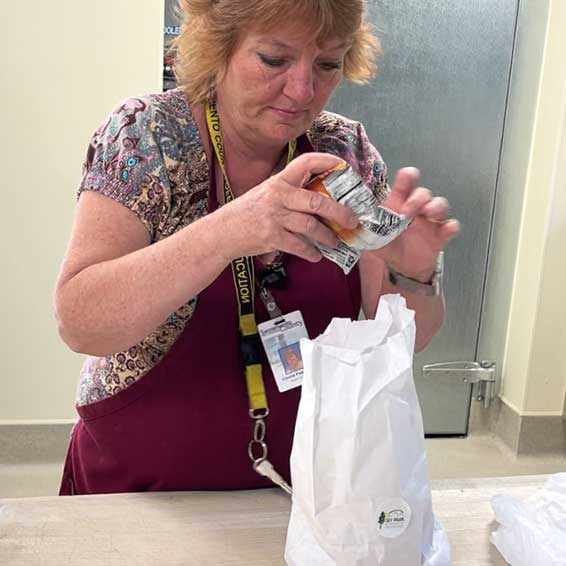 Staff member putting food in a paper lunch bag