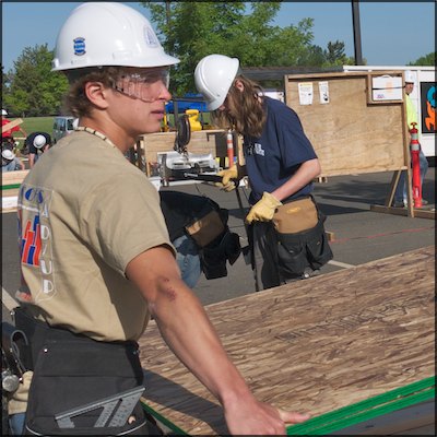 Student carrying sheets of plywood