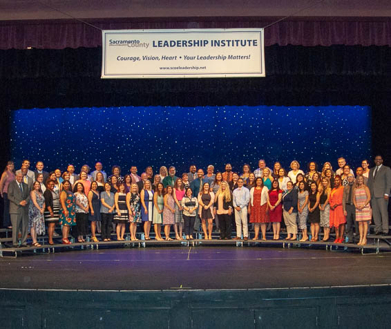 Large group of Leadership Instute graduates posing on-stage