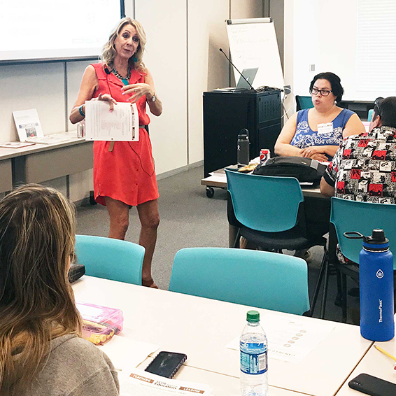 Instructor holding paper and gesturing to seated students