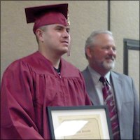 Parolee in cap and gown receiving certificate