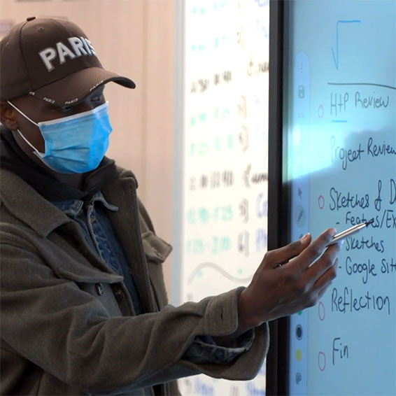 Instructor writing on a board in front of class