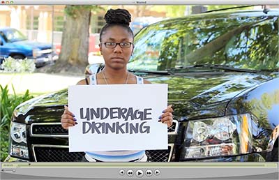 Video screenshot with female student holding underage drinking sign