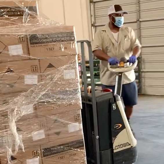 Worker moving pallet of cardboard boxes