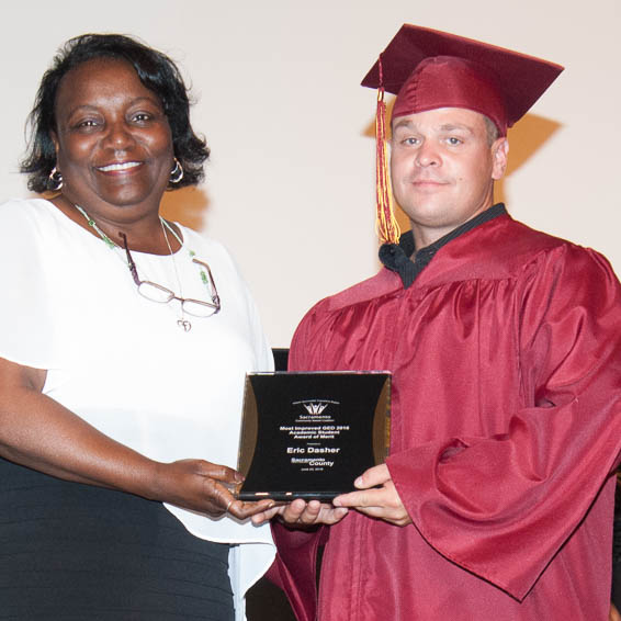 Graduate in cap and gown receiving plaque