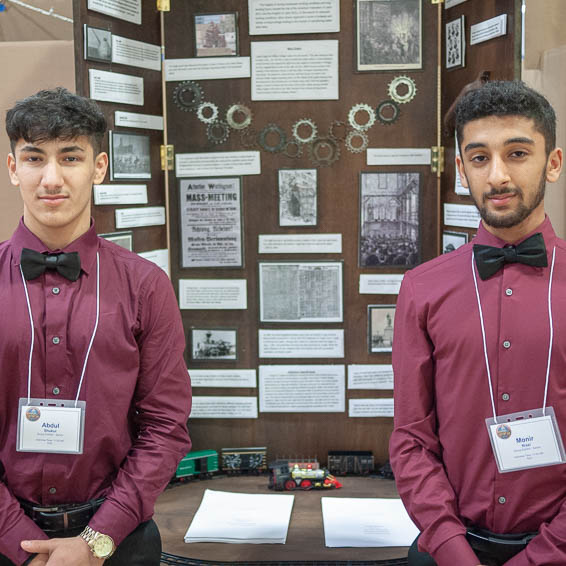 Two students posing in front of project display