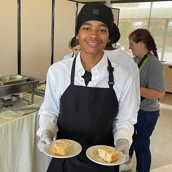 Smiling student holding plates of food