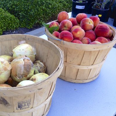 Baskets of fresh peaches and onions for sale