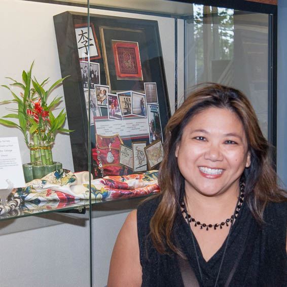 Employee posing in front of shadow box inside glass display case