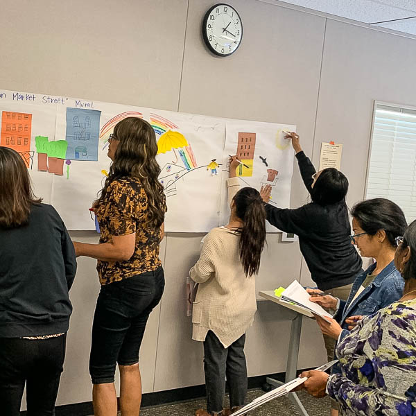 People writing on larger paper on a classroom wall