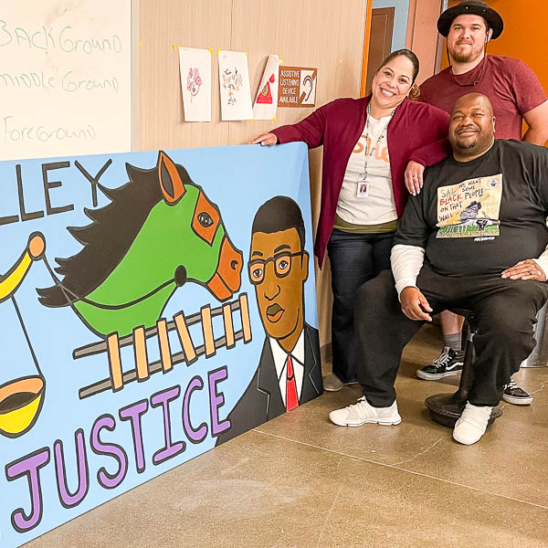 Staff and artist posing with mural