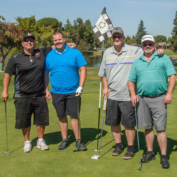 Group of four golfers holding clubs