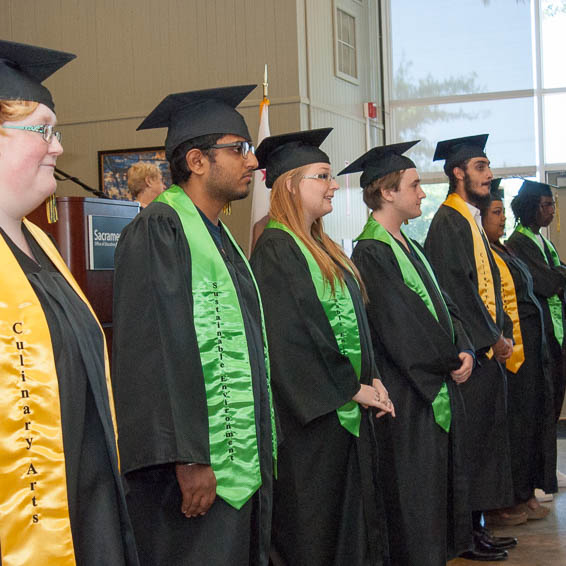 Graduates in caps and gowns standing in front of audience