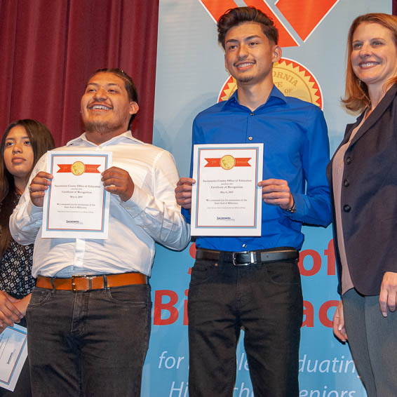 Students holding certificates with teacher