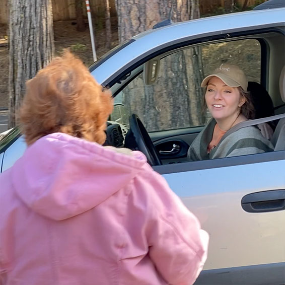 Staff member talking to parent through car window