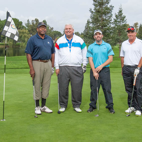 Golfers posing at hole with flag
