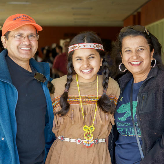 Student wearing Native American style clothing posing with family