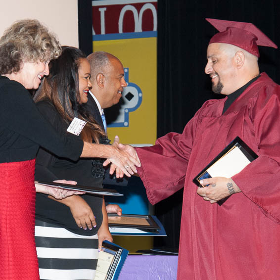 Graduate in cap and gown shaking hands with dignitaries