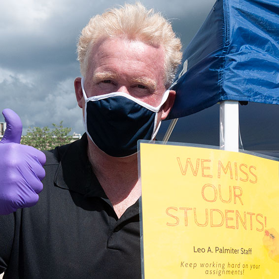 Staff member next to sign: We miss our students. Keep working hard on your assignments.