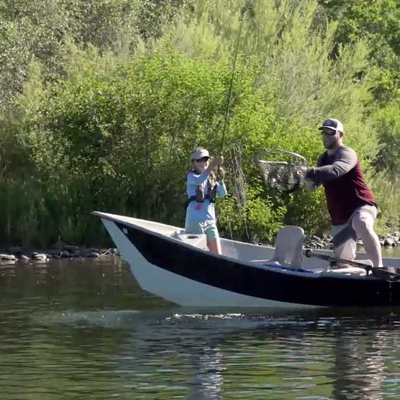 Father and daughter catching a fish from the American River in a small boat