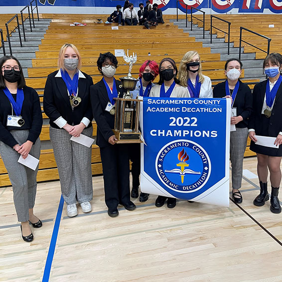 Students holding trophy and champion banner.