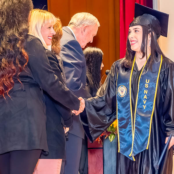 Board trustees shaking hands with a graduate